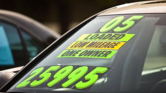 Stickers on the windshield of a car for sale at a used car dealership.
