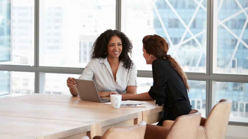Two Businesswomen Using Laptop In Boardroom Meeting.