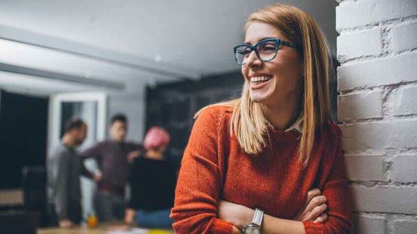Portrait of an young female team leader, entrepreneur, standing in the office, smiling.
