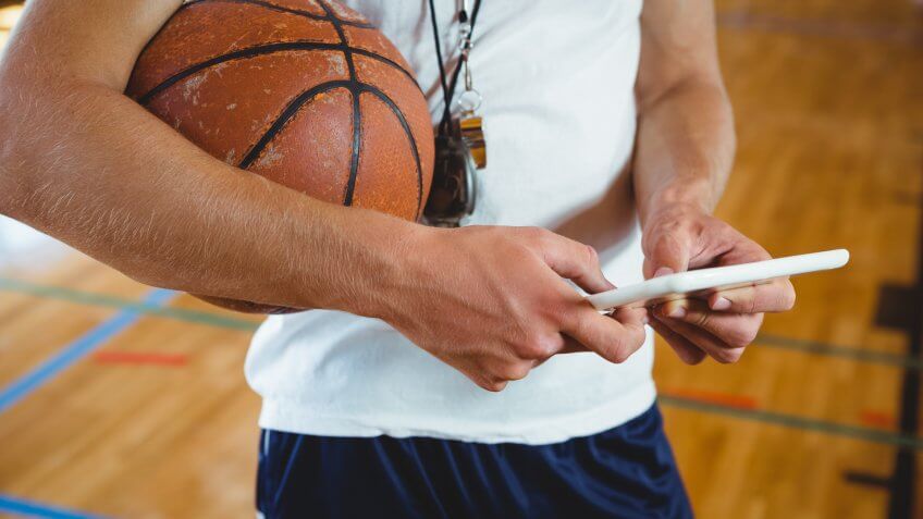 Close up midsection of male coach using digital tablet while standing in court.