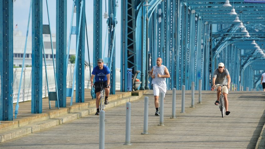 "Chattanooga, United States - June 12, 2012 : An unidentified male runner is overtaken by two unidentified male cyclists on the Walnut Street Bridge, Chattanooga, Tennessee, USA.