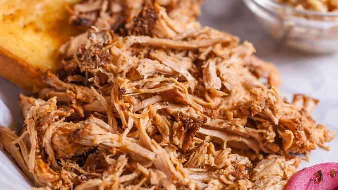 Close up shot of pulled pork fibers in a sandwich freshy served on a platter.