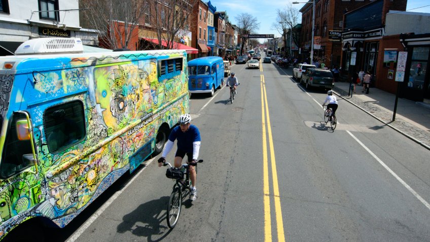 Philadelphia, PA, USA - April 12, 2014; Cyclist ride past food trucks that line both sides of Main Street.