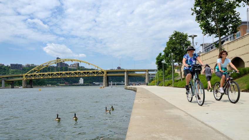 "Pittsburgh, Pennsylvania, USA - June 3, 2012: Cyclists on the North Shore of the Allegheny river on a sunny summer day.