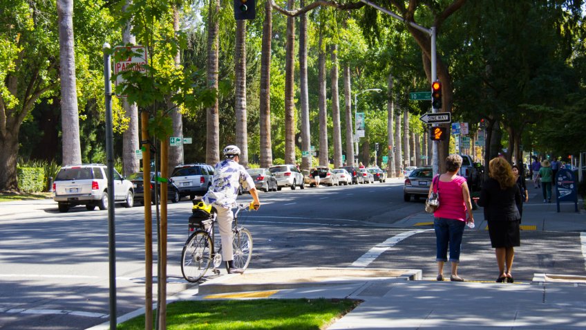 People traveling in city by foot and by bike.