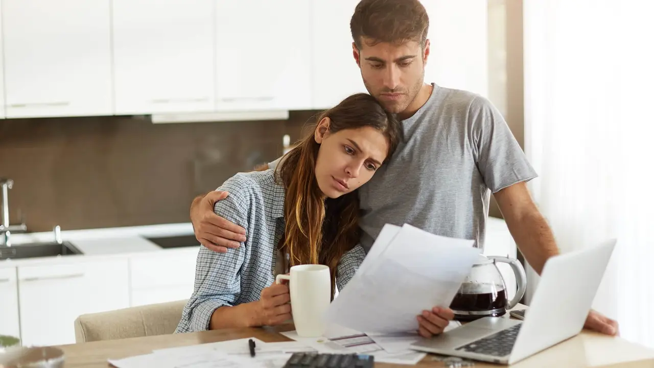 A young couple lamenting over finances and showcasing money regrets.