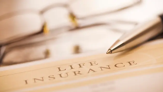 "Document entitled life insurance, a pen and glasses on a desk.