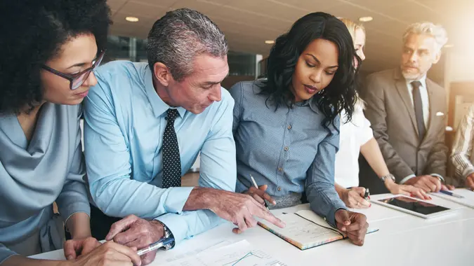 Black and white group of people doing teamwork in contemporary office.