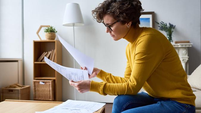 Concentrated woman reviewing financial documents at home.