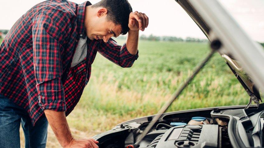 Tired man tries to repair a broken car.