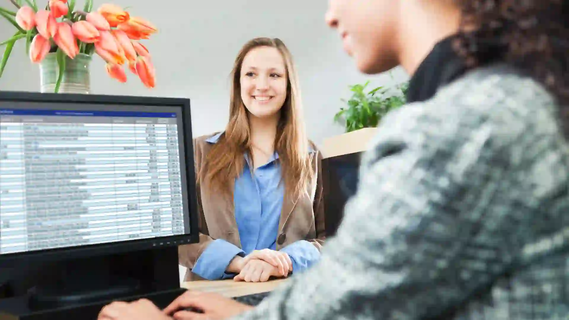 A young woman bank customer making a financial transaction with a bank teller over the counter in a retail bank