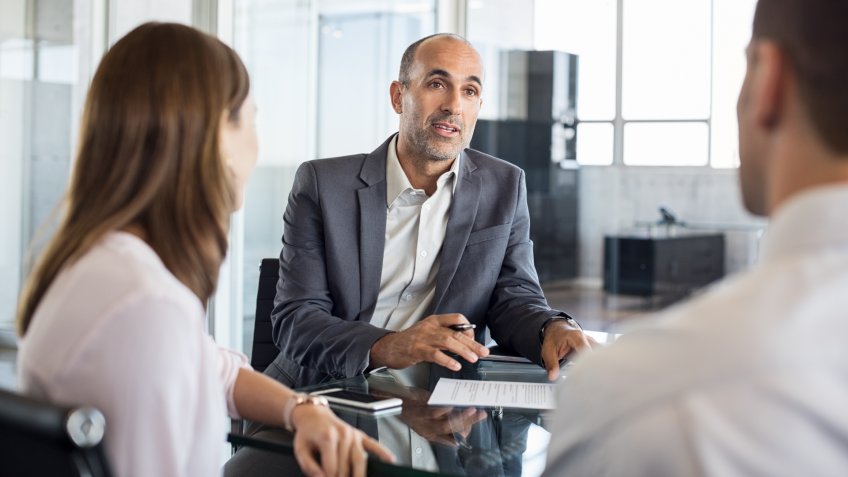 Mature financial agent showing new investment to young couple