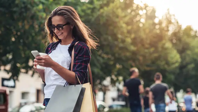 Young woman texting while enjoying a day shopping.