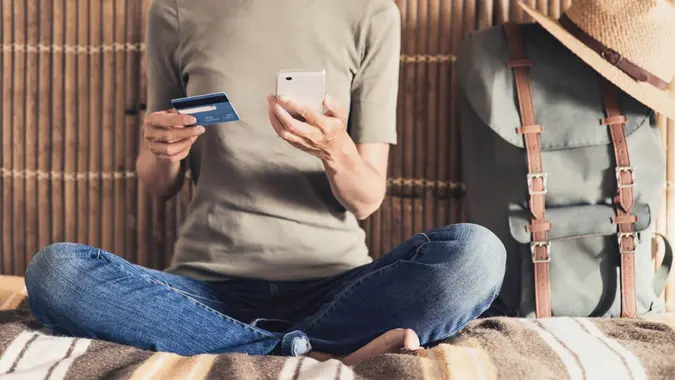 woman on vacation using smartphone and credit card