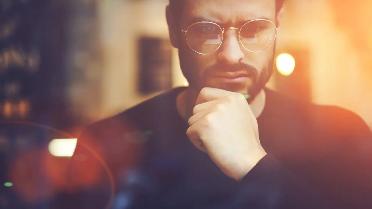 Cropped close up image of pensive bearded entrepreneur in optical spectacles for better views dressed in black sweatshirt.