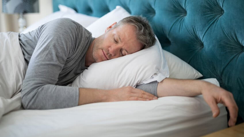 Man sleeping on bed in bedroom at home.