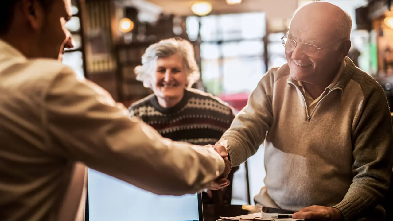 senior man shaking hands with financial advisor.