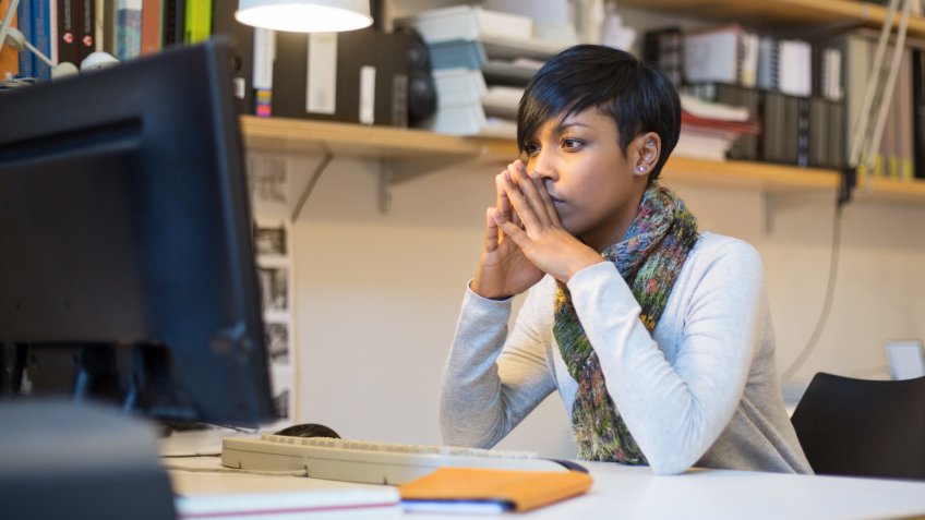 Shot of an young woman sitting and thinking at her desk in startup office.