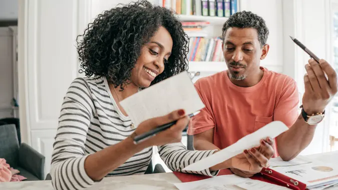 Couple in the kitchen with receipts and laptop.