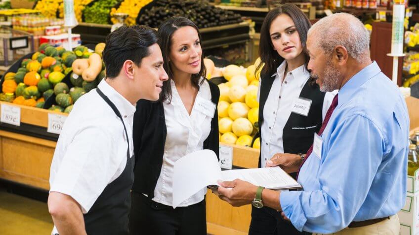 Businessman and workers talking in grocery store.