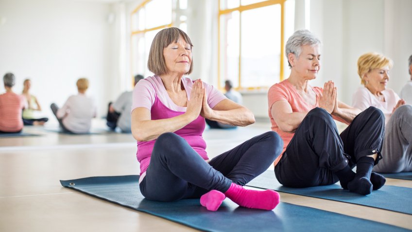 Relaxed senior women meditating in yoga class.