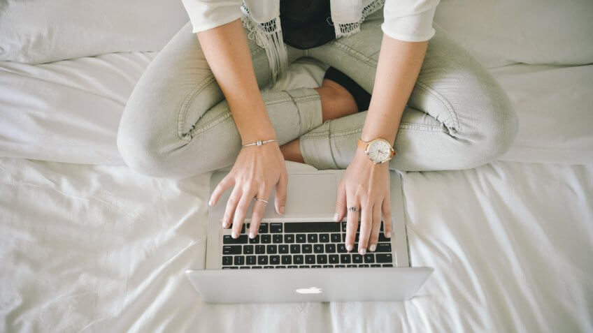 woman on bed blogging on laptop