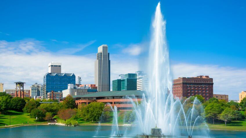 Downtown Omaha skyline in the background with a huge and elaborate fountain and a lake in the foreground (part of the Heartland of America park.