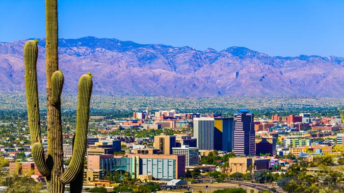 Tucson Arizona skyline cityscape framed by saguaro cactus and mountains.