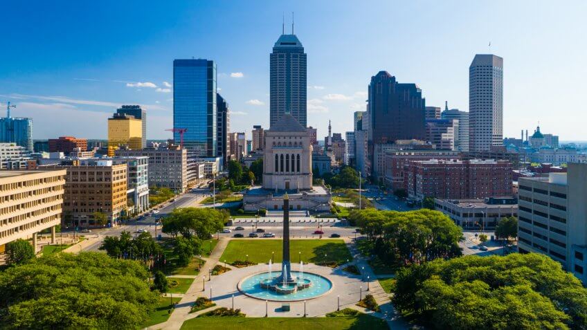 Downtown Indianapolis skyline with the Depew Memorial Fountain, obelisk, park, and the Indiana World War Memorial in the foreground.