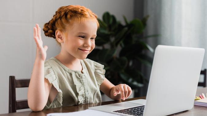 beautiful little girl with laptop making video call.