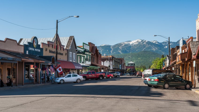 Whitefish, Montana, USA - May 29, 2009 : view of the main street of Whitefish city in Montana with houses, stores, cars.