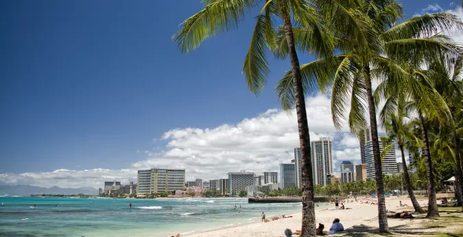 A wide shot of Honolulu, Hawaii from the beach to showcase the city, vacation potential and tropical setting.