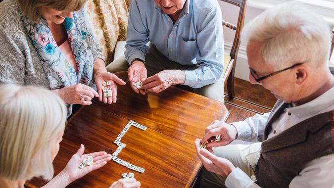 Group of senior friends are playing dominoes at a table together.