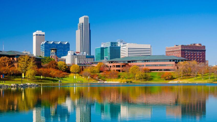 Omaha downtown skyline during Autumn, with a lake at the Heartland of America Park in the foreground.