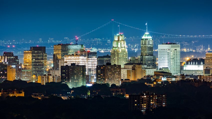Newark, NJ, skyline on a hazy night with Verrazano Narrows bridge in the background.