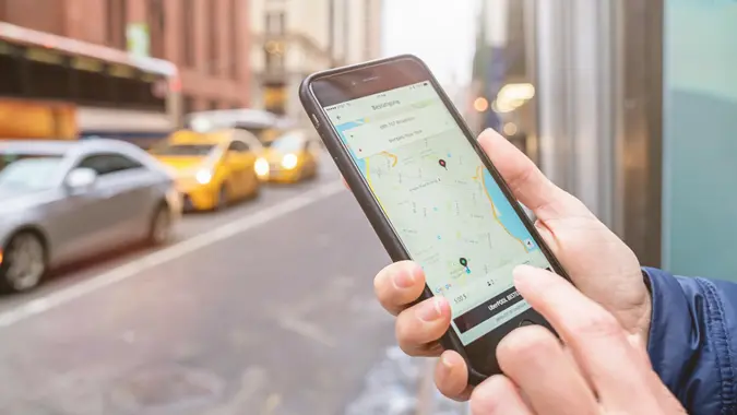 New York City, USA - May 6, 2016: Businesswoman using the famous Uber Taxi Cab App on an Apple iPhone 6s Plus in the streets of New York City.