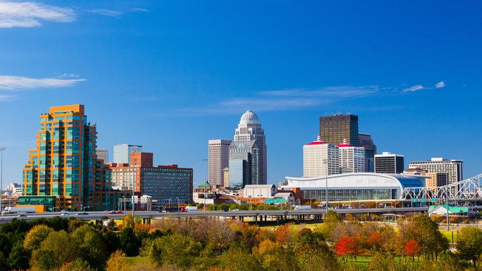 7. Louisville, Ky. -- $57,285 Louisville downtown skyline view with a park with trees in the foreground.