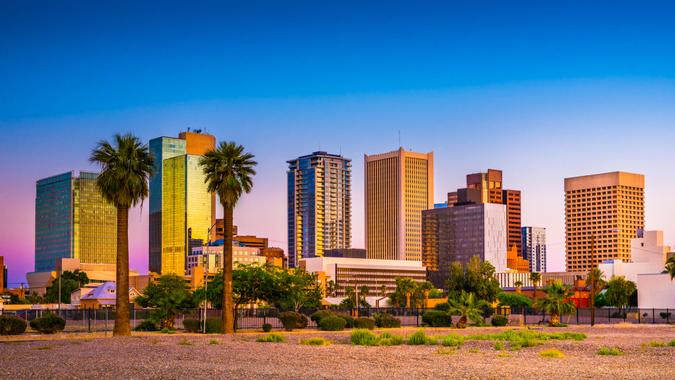 Downtown skyscrapers with palm trees and greenery in Phoenix, Arizona during sunset.