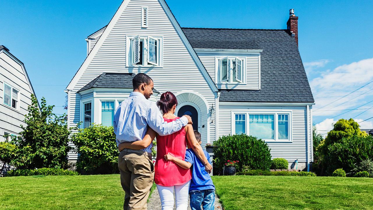 Photo of a young mixed-race family admiring a home - possibly their first home, or the home the hope to own.