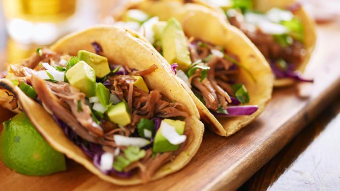 street tacos in corn tortilla, topped with garnishes of onion, cilantro, and avocado