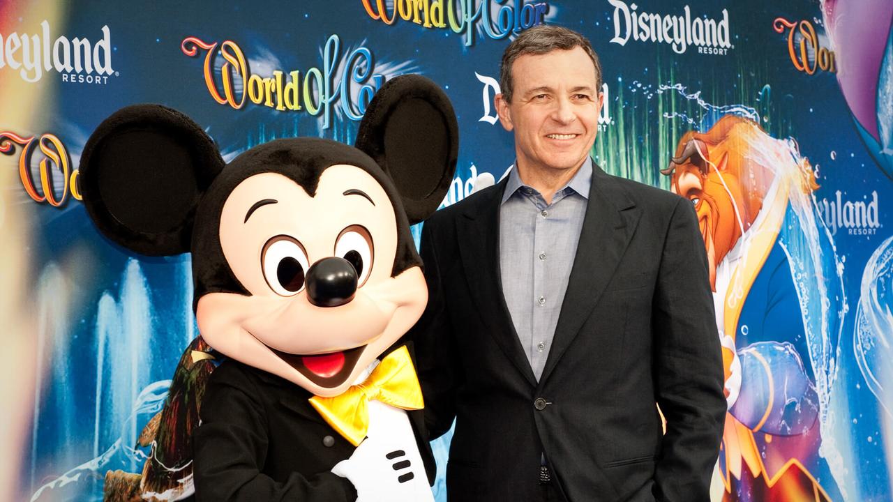Bob Iger poses for a picture with a person in costume as Mickey Mouse