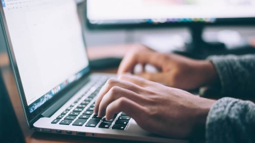 Hands typing on a laptop