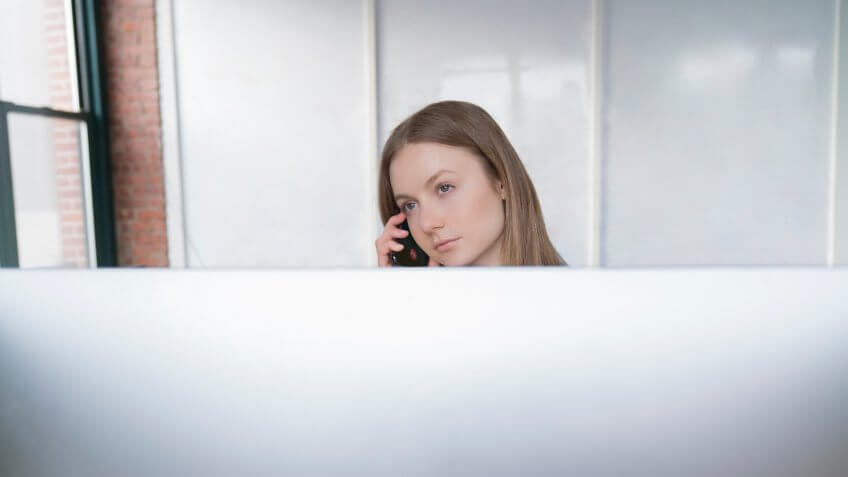Young woman bored at a job taking a phone call
