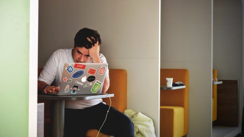 Young man stressed about work on laptop