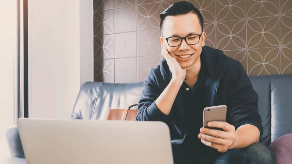 Stock, shares, NASDAQ, S&P 500, money, Happy asian businessman using smartphone while sitting on sofa at home office background with vintage filter.