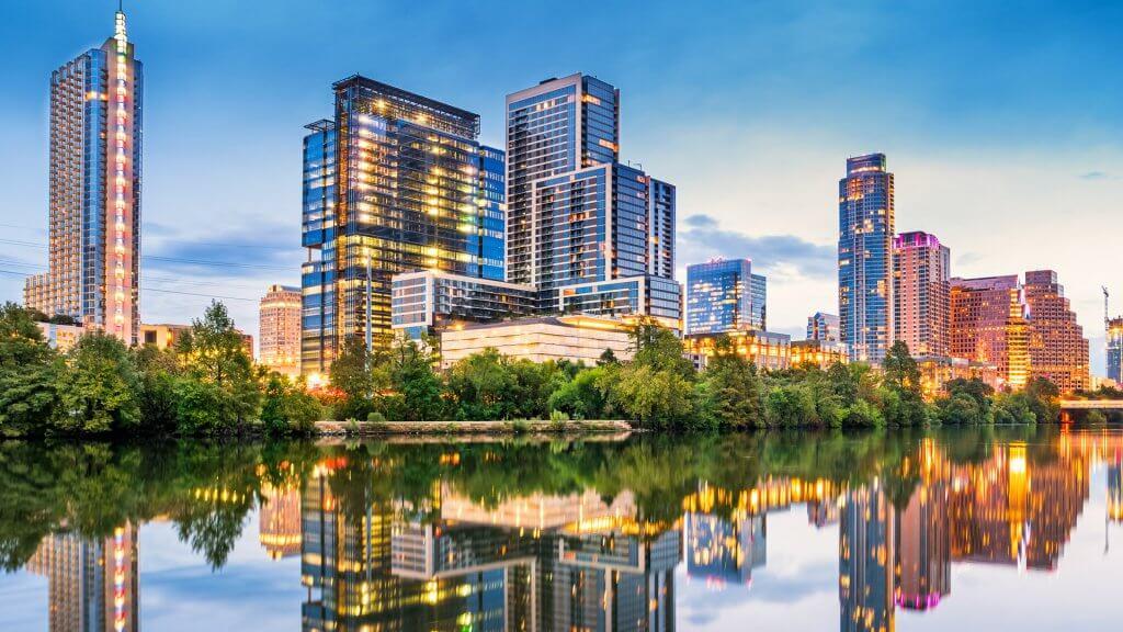 Stock photo of the skyline of downtown Austin, Texas, USA with apartment buildings and office buildings, reflecting in the Colorado River during the dawn twilight blue hour.