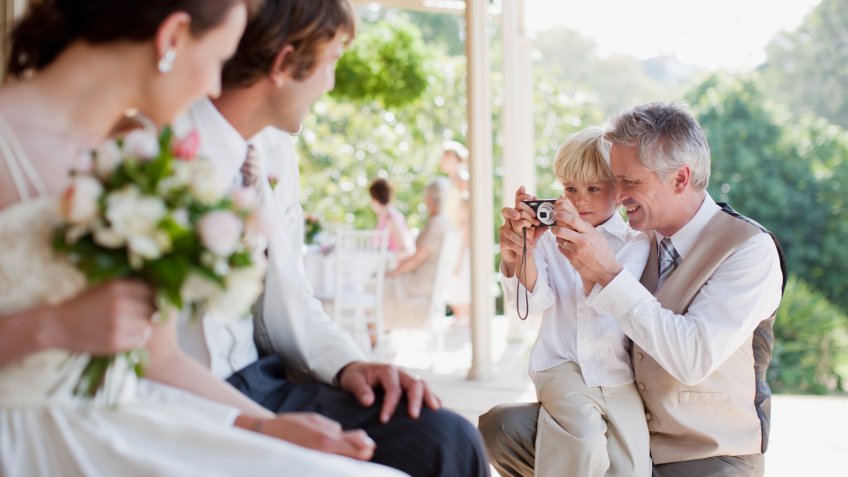 Father and son taking picture of bride and groom.