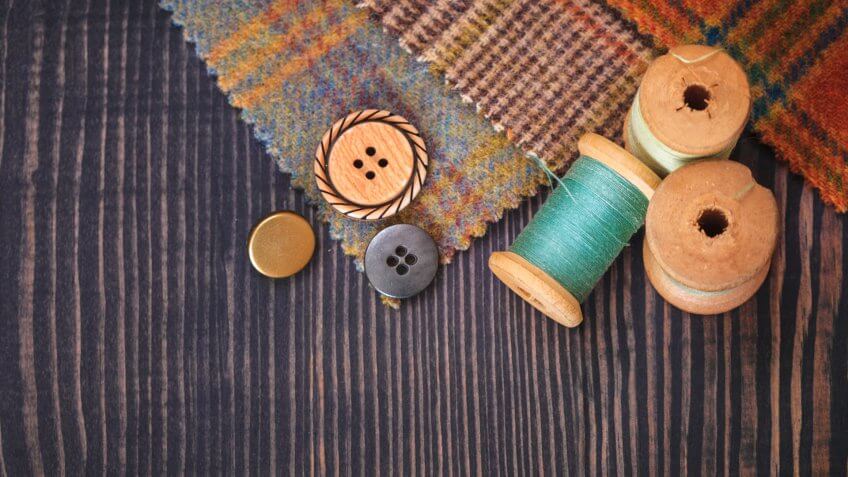 Stock, shares, NASDAQ, S&P 500, money, Thimble, buttons, spools of thread and fabric swatches on a wooden background close up.