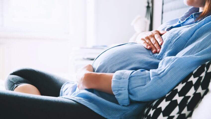 Pregnant woman in denim shirt relaxing on couch