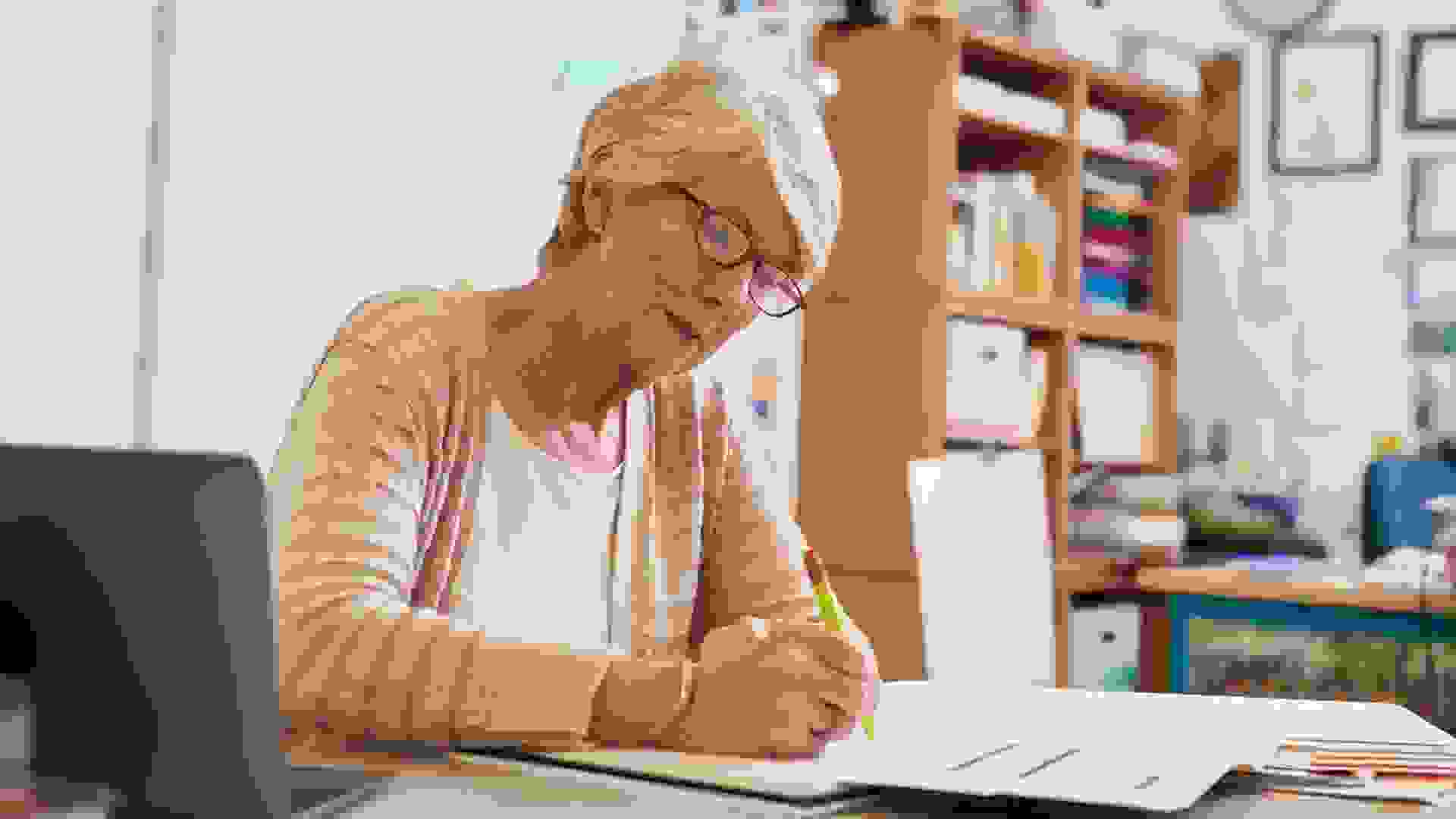 Mature woman working on documents at desk in office